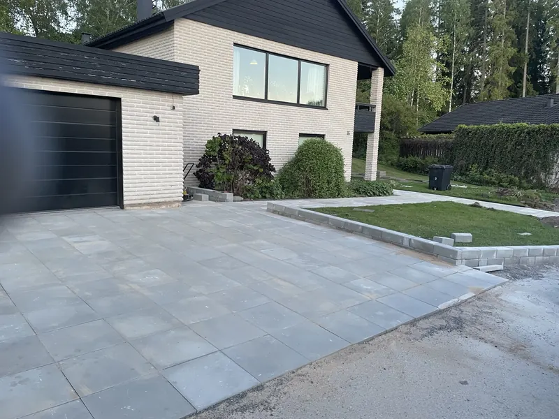 Stenläggning framför ett vitt hus